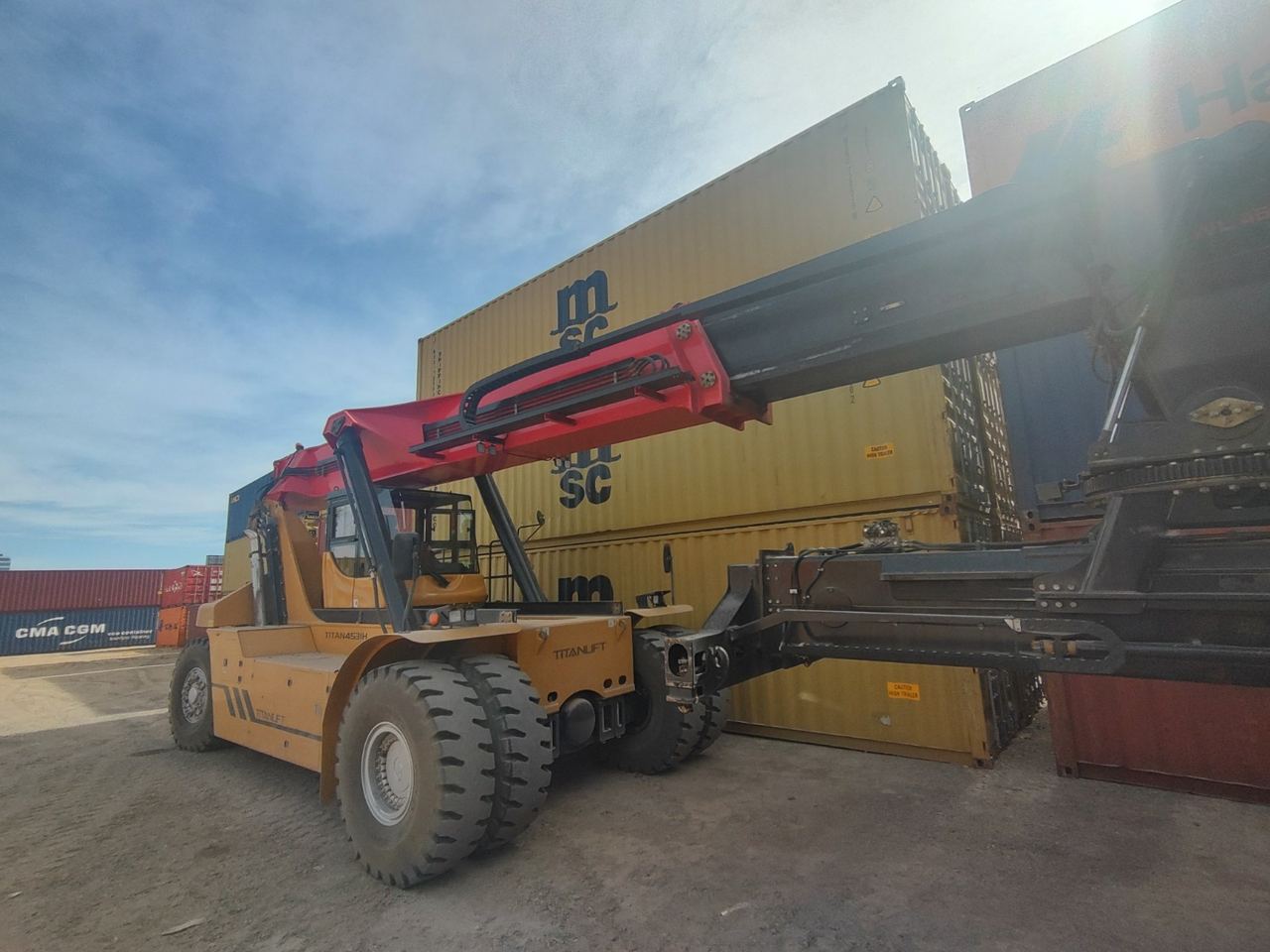 Containera reach stacker de JB moviendo un contenedor en la playa
