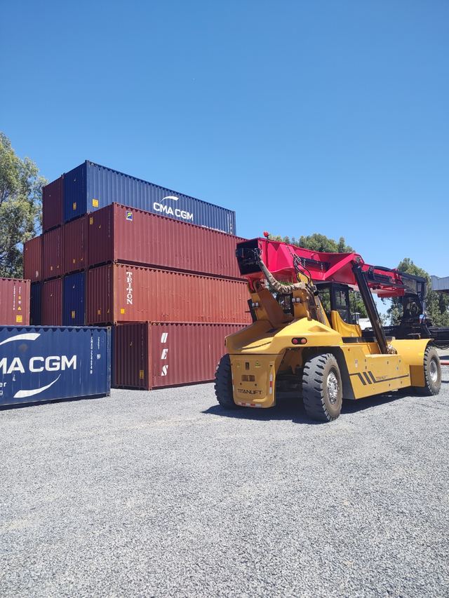 Containera apilando contenedores en la playa