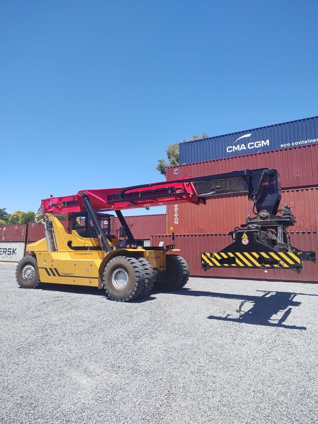 Containera reach stacker de JB frente a contenedores apilados en la playa
